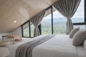 a bedroom with a large bed with large windows at Solitude Villas in Ban Chang Talut