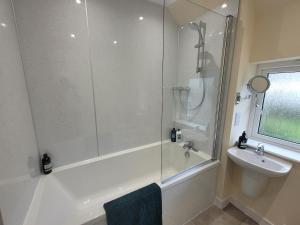 a white bathroom with a shower and a sink at Riverside Home Kinlochleven in Kinlochleven +25 photos