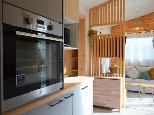 a kitchen with a microwave and a living room at Tiny Twins - TinyHouse 6 personnes à Malmedy by LaConciergerie in Malmedy