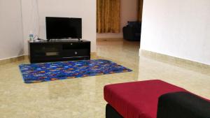 a living room with a flat screen tv and a rug at Noor Guesthouse in Kampong Alor Ganu