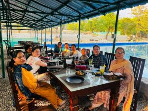 a group of people are sitting at a table at Mhara Himachal in Bīr