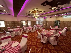 a banquet hall with white tables and chairs and purple lighting at Hotel Srinivas in Jodhpur