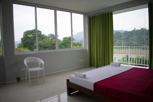 a bedroom with a bed and a chair and windows at The Cliff Kandy in Gonawatta