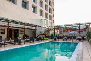a swimming pool with tables and chairs next to a building at Hotel Grand Rio in Nashik