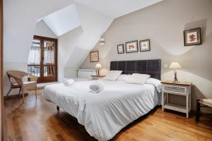 a bedroom with a large white bed and a chair at Gaudioso by Cardi Suites in Sallent de Gállego