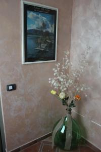 eine Vase mit Blumen in einem Raum mit einem Gemälde in der Unterkunft Hostel del Gal in Clusane sul Lago