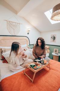 two women sitting on a bed with a table at Hotel Zon in Serdivan