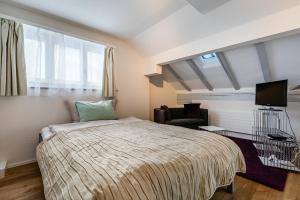 a bedroom with a bed and a chair and a television at Apartments Sank Georgenstrasse in St. Gallen