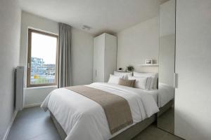 a white bedroom with a large bed and a window at West Bay Apartments in Middelkerke +83 photos
