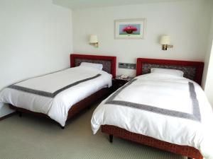 two beds in a hotel room with white and red at ホテルマルセイユ in Shimoda