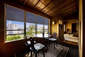 a room with a table and chairs and a large window at Yamatoya Besso in Matsuyama