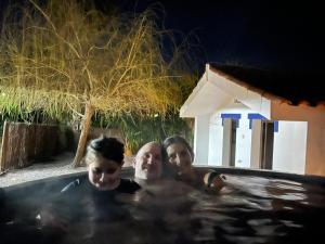 three people in a swimming pool at a resort at Alentejo Villa Nordic Spa & Pool in Santo António do Alcôrrego