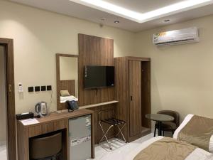 a room with a bed and a tv on the wall at منازل الثقة in An Nikāshah