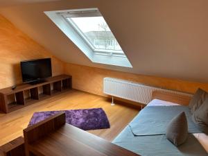 a attic room with a bed and a television at Ferienwohnung2 Renate Strohhöfer in Hirschaid
