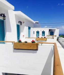 a white house with blue doors and flowers on a balcony at Little Blue Doors Studios in Samos