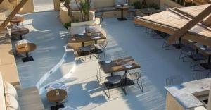 a pool with tables and chairs on a patio at Little Blue Doors Studios in Samos