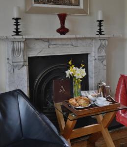 a living room with a table with a fireplace at Taunton House Hotel in Taunton