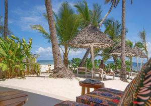 a beach with chairs and umbrellas and the ocean at Private Beach Front 2-Bedroom Apartment, Groundfloor in Kiwengwa