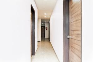 a hallway with white walls and a wooden door at Super Hotel O Tagore Park Laskarhat Formerly Shankar Guest House in Kolkata