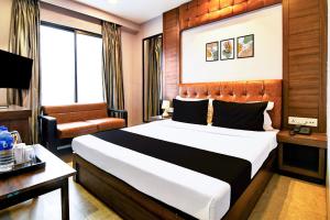 a hotel room with a bed and a chair at Super Hotel O Tagore Park Laskarhat Formerly Shankar Guest House in Kolkata