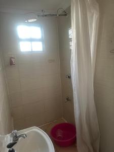a bathroom with a shower with a sink and a red toilet at Brighton court in Jomo Kenyatta Airport Nairobi