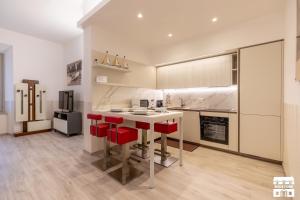 a kitchen with a white counter and red chairs at SANTA MARTA by Design Studio in Bellano