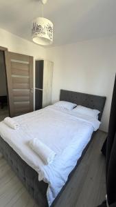 a large bed with white sheets and a chandelier at Lion Crib in Bacău