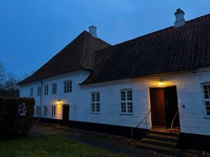 a white house with lights on the side of it at Estrup Hovedgaard in Vejen