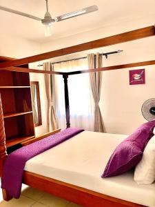 a bedroom with a bed with purple pillows and a window at Magenta Apartment in Diani Beach