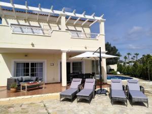 a house with chairs and an umbrella next to a pool at Villa Elegante, with a private pool in Murcia
