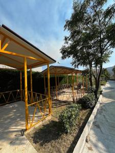 a building with a pavilion with a tree and a sidewalk at Caco Camper Parking in Berat