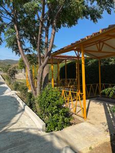 a yellow pavilion with a tree and a street at Caco Camper Parking in Berat