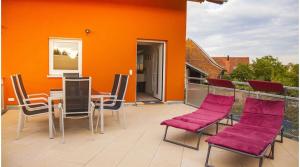 a patio with a table and chairs and an orange wall at Ferienwohnung Leppert in Schwanau