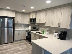 a kitchen with white cabinets and a stainless steel refrigerator at Authentic Suite in YYC