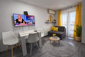 a living room with a couch and a tv on the wall at Iva Penthouse in Novi Sad