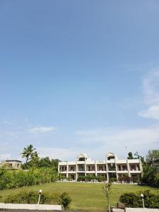 a large white building with a green yard at Camp Leo Aaranya Resort in Sasan Gir
