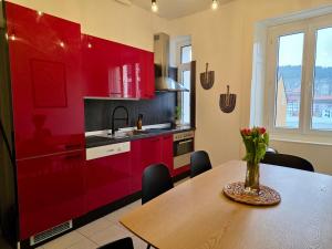 a kitchen with red cabinets and a table with flowers on it at La Maison de Jacob in La Chaux-de-Fonds +17 photos