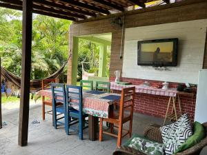 a patio with a table and chairs and a tv on the wall at Calhetas Suíte 2 in São Sebastião