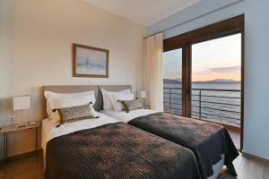 two beds in a hotel room with a large window at Seafront Marine Villa with private sea access - Iris Villas Lefkada in Sivota