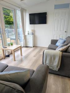 a living room with two couches and a flat screen tv at 147 Snowdon Drive, Glan Gwna Holiday Park in Caernarfon