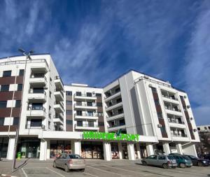 a large white building with cars parked in a parking lot at Daluxst apartman in Vrnjačka Banja