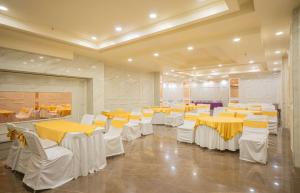 a banquet hall with yellow tables and white chairs at Hotel Magenta-City Center Bani Park Jaipur in Jaipur +28 photos