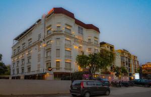 a large white building with cars parked in front of it at Hotel Magenta-City Center Bani Park Jaipur in Jaipur
