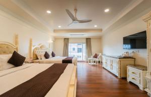 a bedroom with two beds and a ceiling fan at Hotel Magenta-City Center Bani Park Jaipur in Jaipur