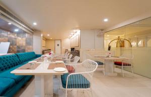 a restaurant with tables and chairs and a blue couch at Hotel Magenta-City Center Bani Park Jaipur in Jaipur