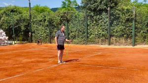 a man is standing on a tennis court at Apartmani Todorovic Ugore Vrdnik in Vrdnik