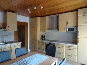 a kitchen with a wooden table and blue chairs at Haus Panorama in Massenbachhausen