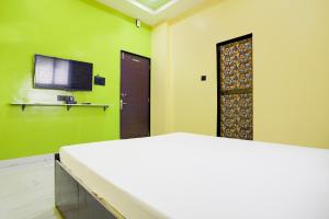 a room with green walls and a tv and a door at Hotel O Raj Guest House in Akola