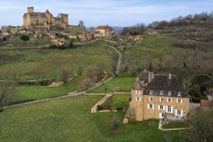 an old house on a hill with a castle in the background at Manoir du Boscau, Gilles del Bosc in Prudhomat