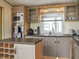 a kitchen with a sink and a microwave at Lavender Lodge in Patrington +24 photos